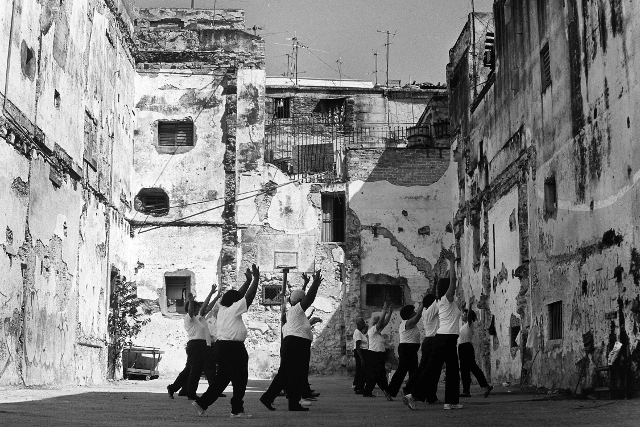 Black and white image of a group of older Cubans taking an exercise class.